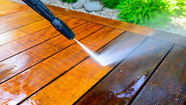 A professional home improvement handyman service pressure washing a house, patio, driveway, and shed.
